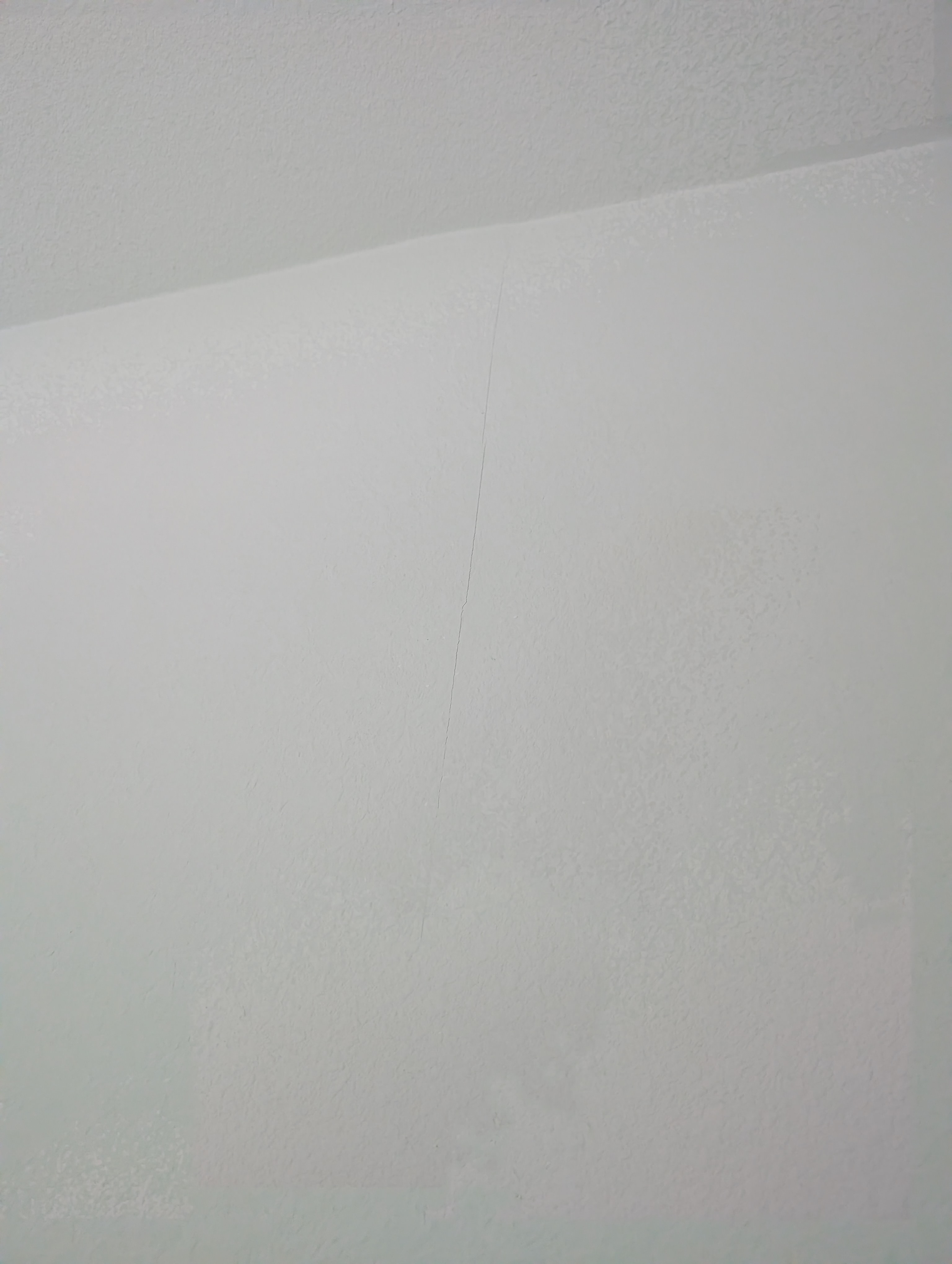A horizontal hairline crack runs along the ceiling-to-wall junction in the living room.