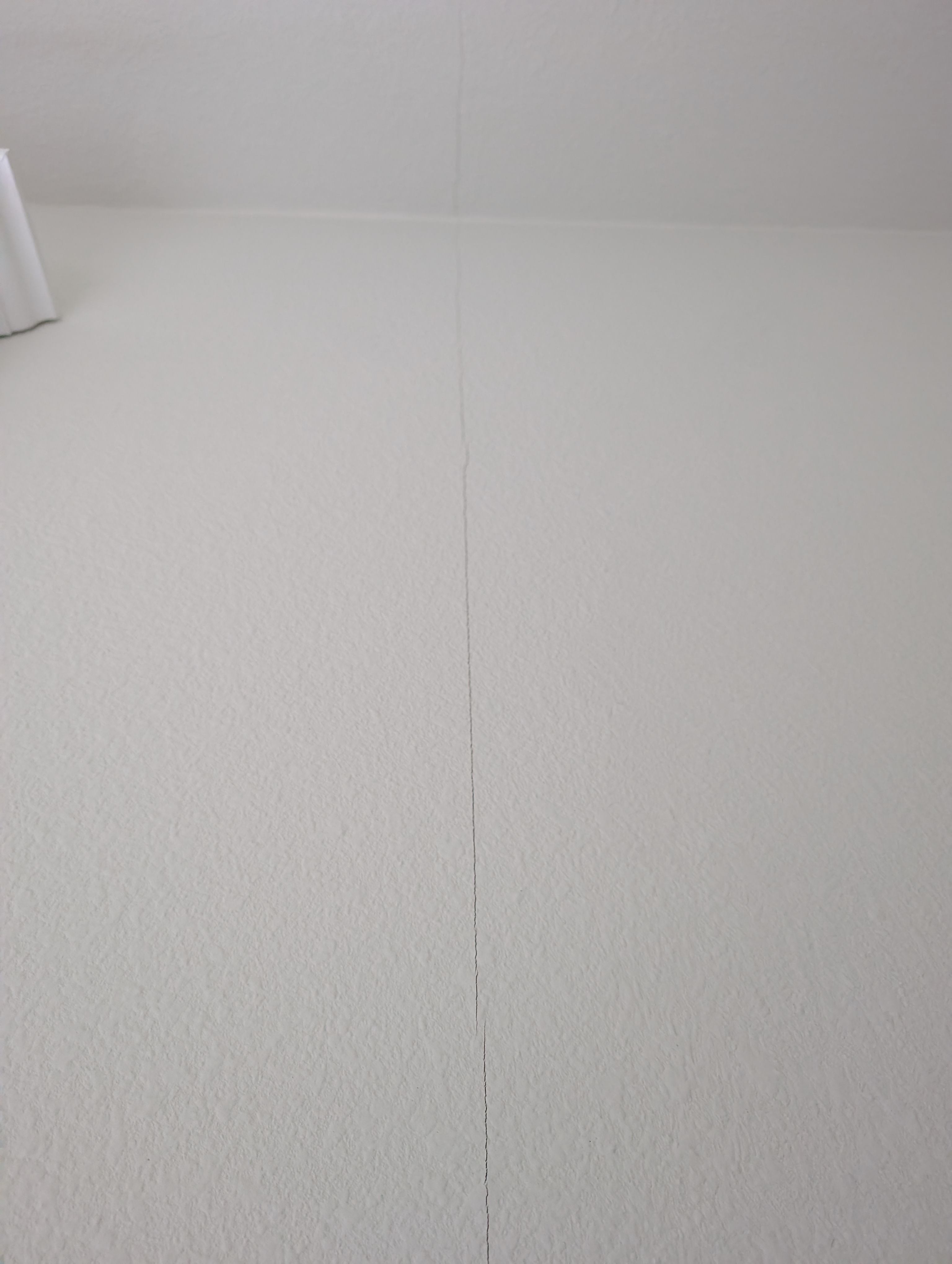A diagonal crack is visible radiating from the corner of a living room wall.