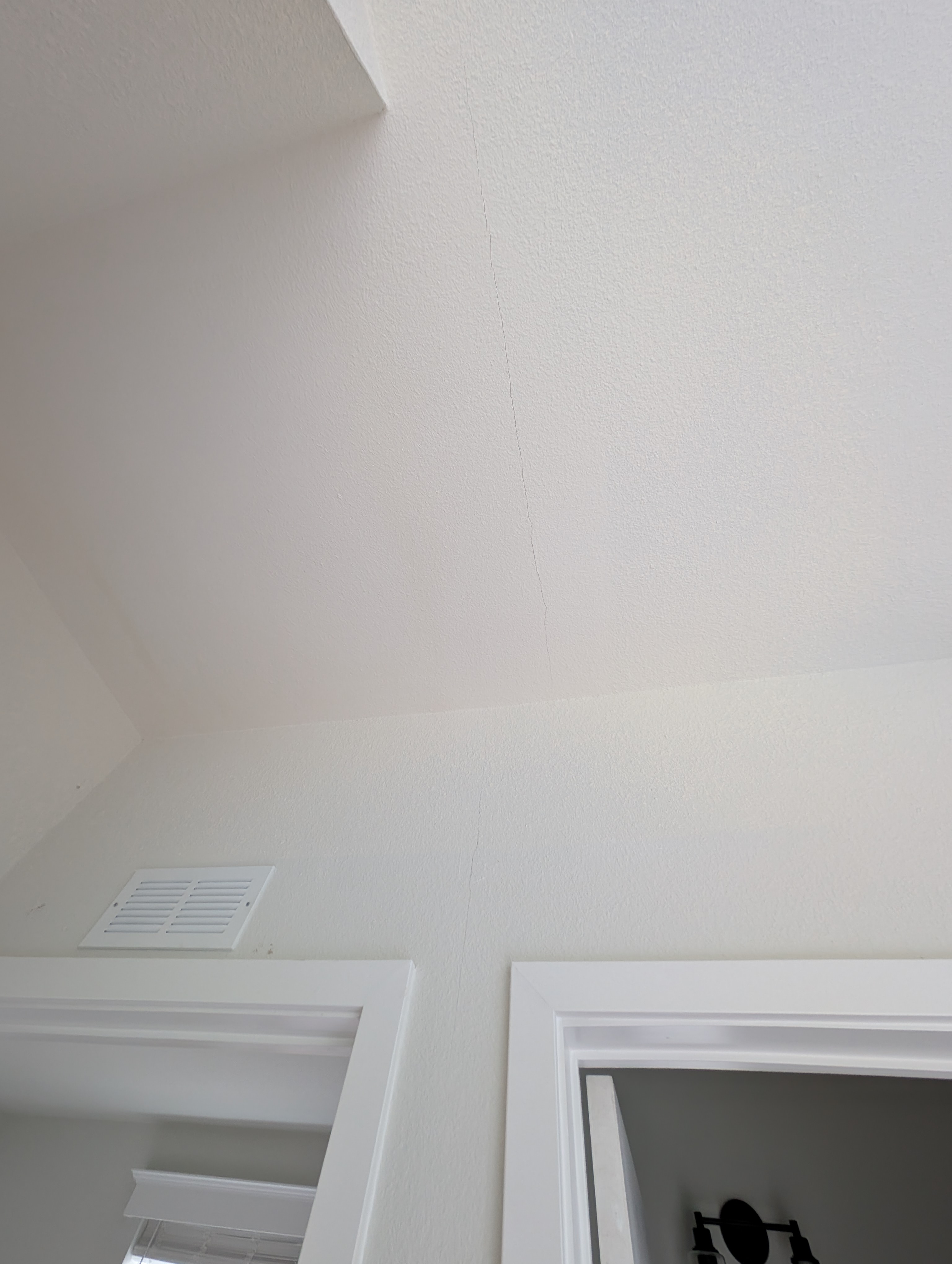 A hairline crack is visible along the ceiling surface in the master bedroom.