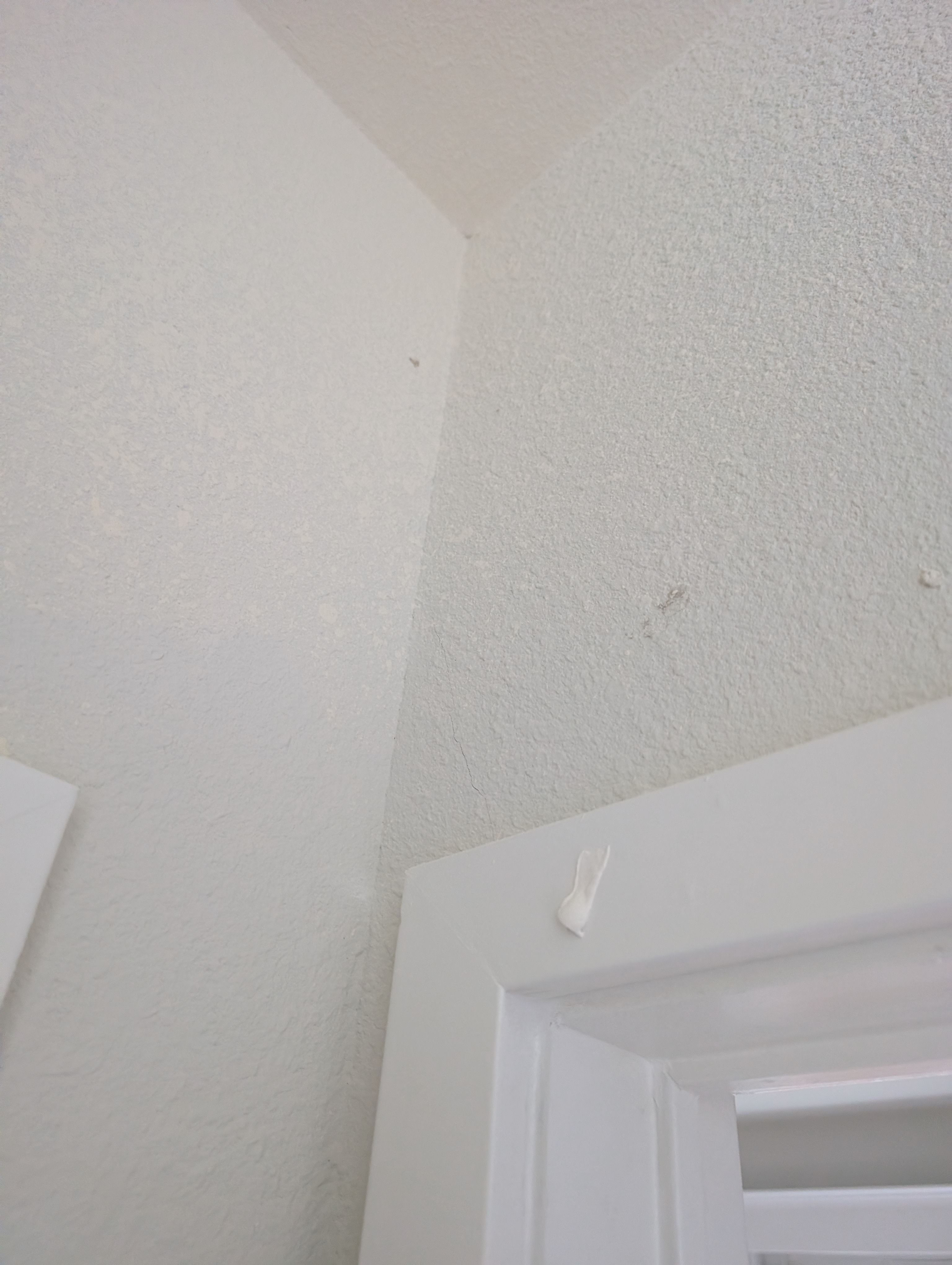 Multiple cracks radiate outward from a wall corner in the bedroom adjacent to the master bedroom.