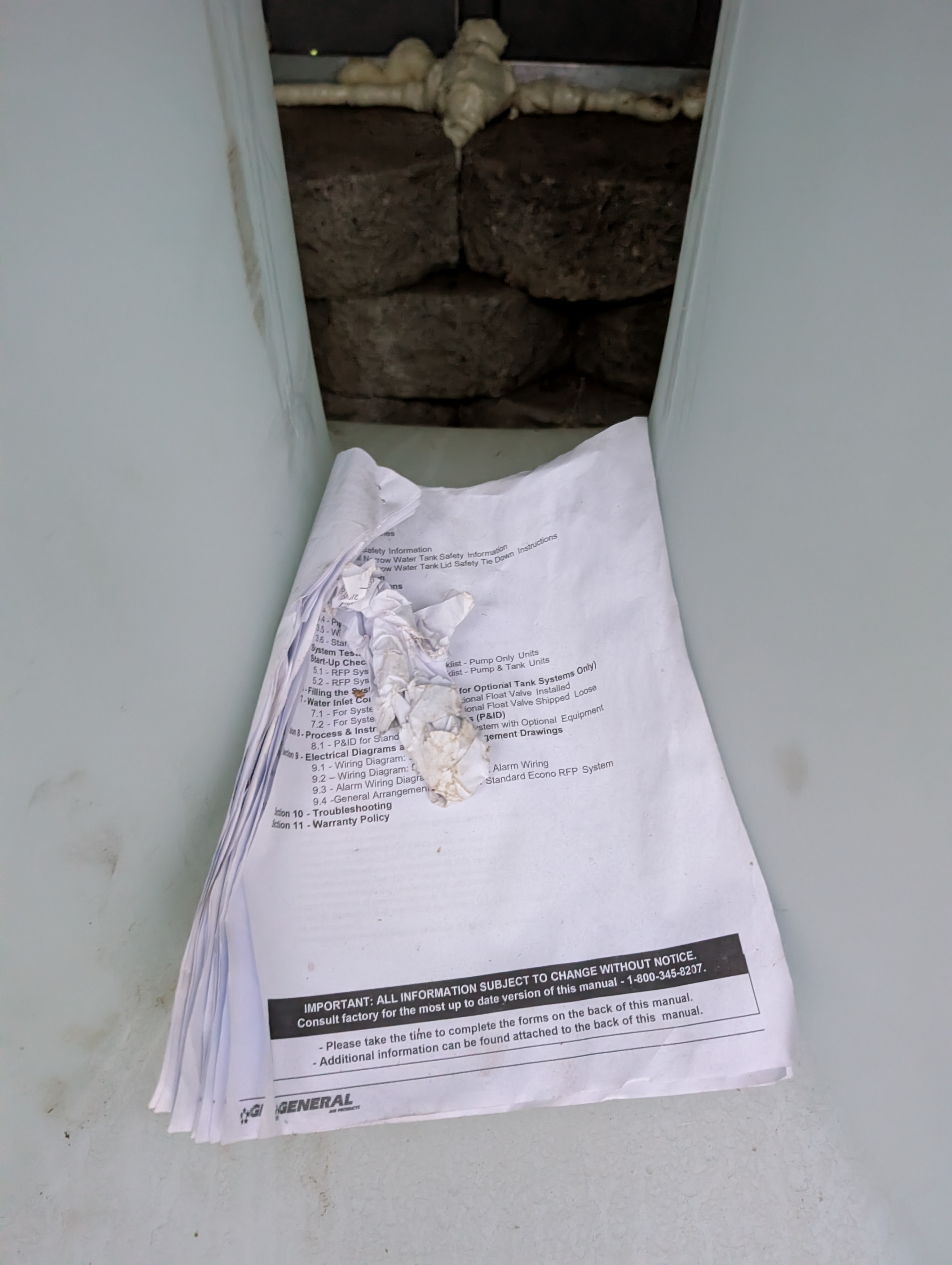 A wider view shows the water heater area with the access panel left open, indicating careless site conditions.